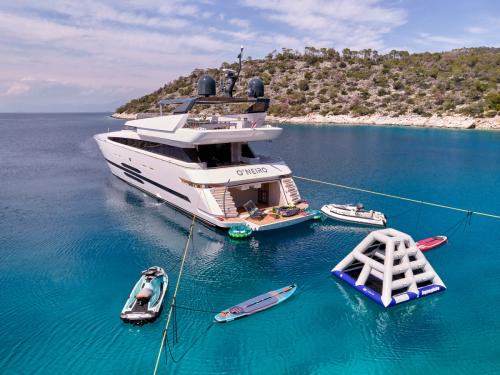 Motor yacht cruising past a Greek island in clear blue water